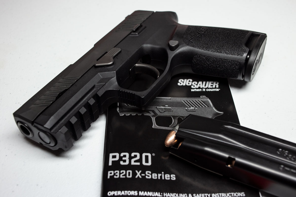 A Sig Sauer P320 with magazine and manual on a white background. Trying some product photography is a great indoor photography project.
